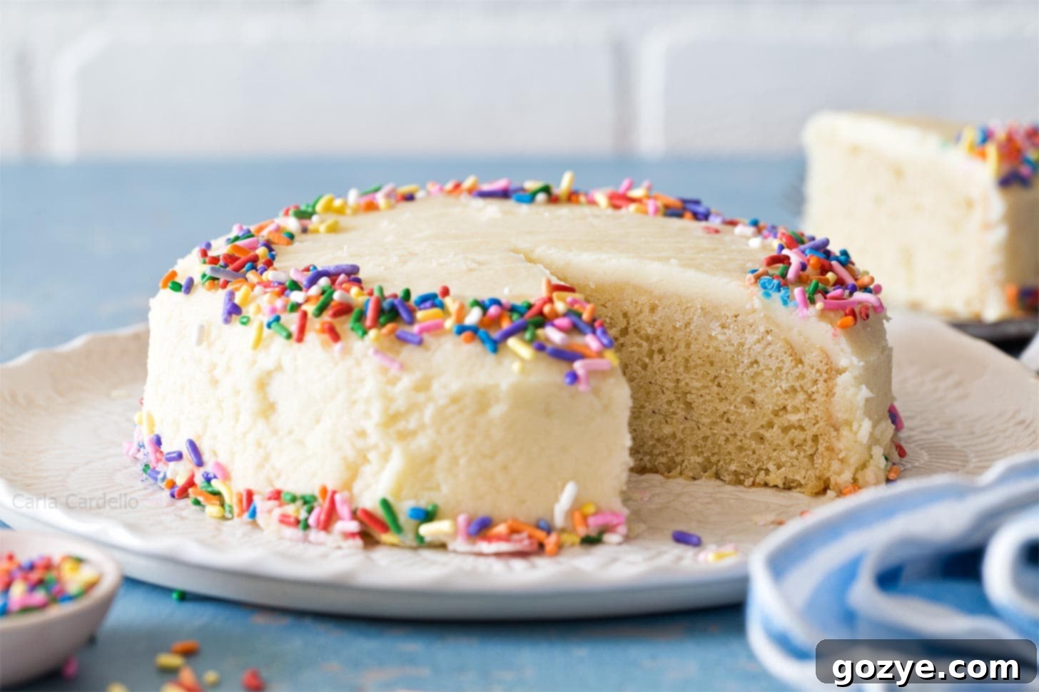 A 6-inch vanilla cake on a white platter, perfectly baked and ready for its finishing touches or serving.