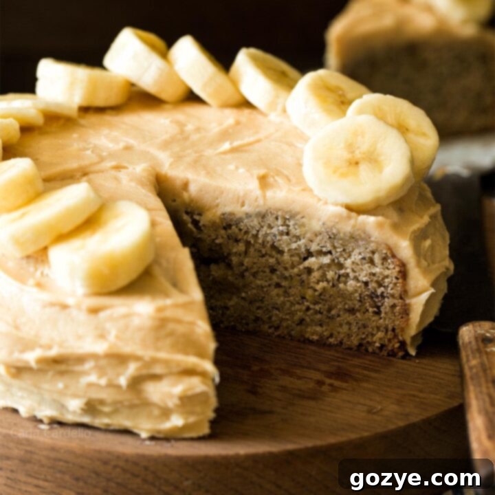 Small Banana Cake on wooden board with slice cut out, showcasing its moist texture