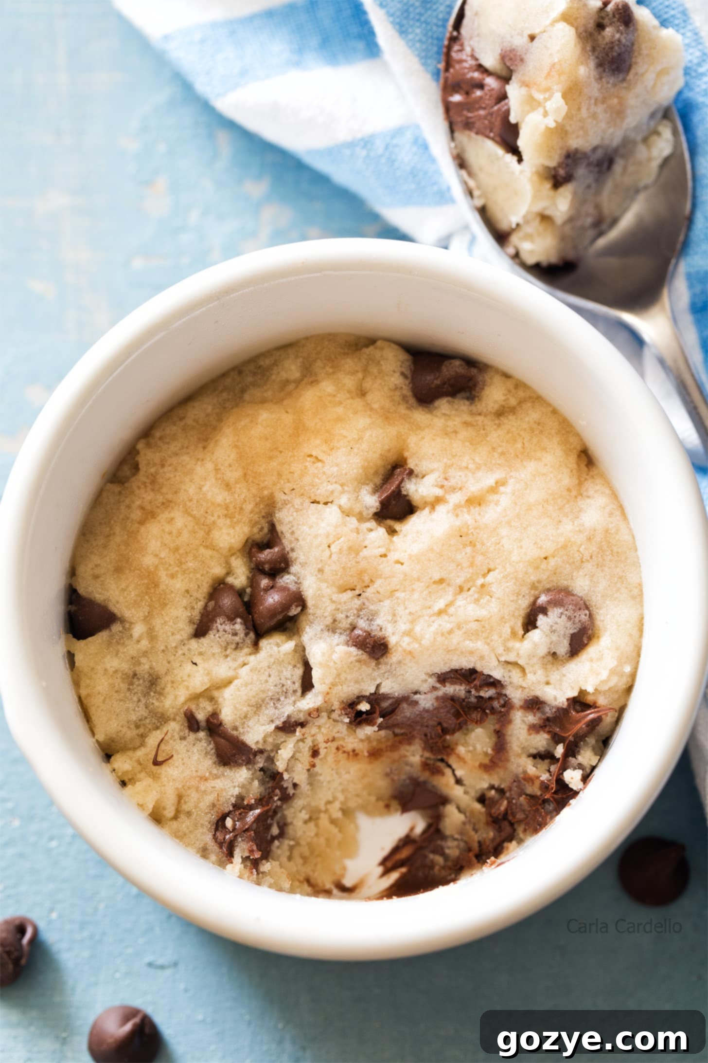 Overhead shot of microwave chocolate chip cookie in a ramekin with a spoon, ready to eat