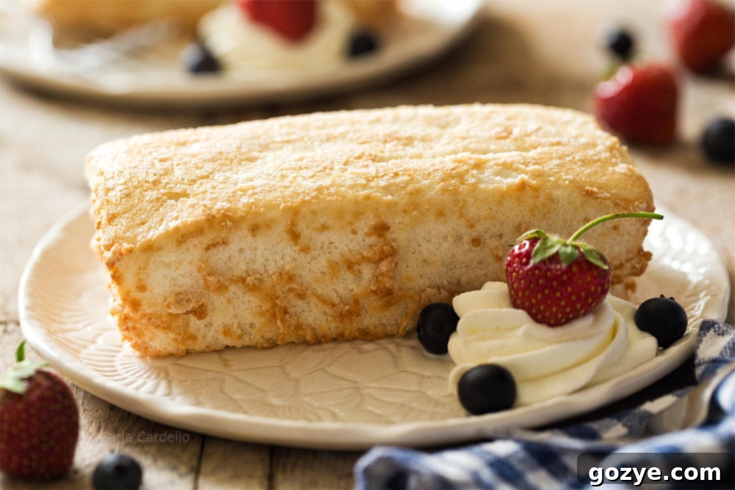 Mini Angel Food Cake on white plate with whipped cream and berries