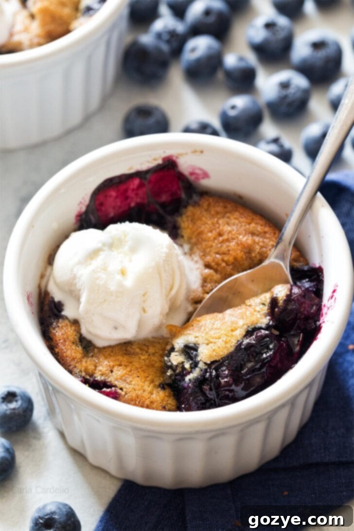 Blueberry Cobbler in a ramekin with spoon digging in