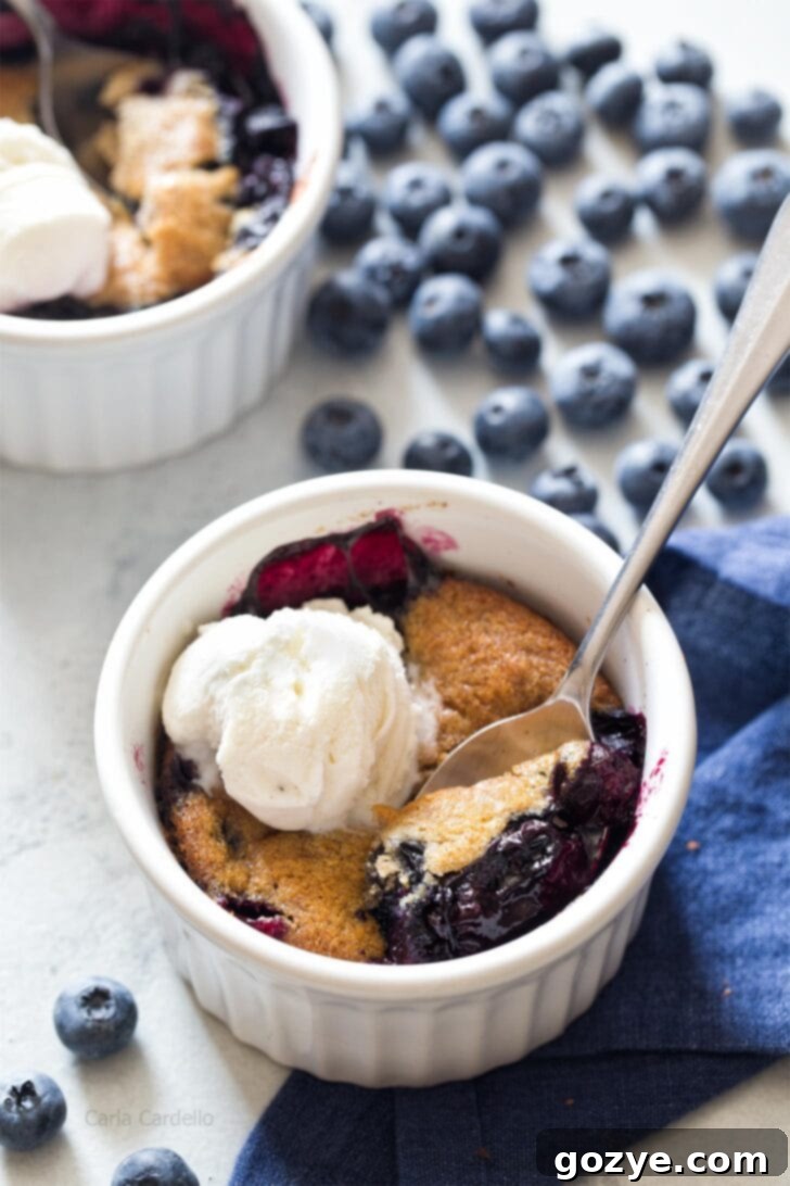Blueberry Cobbler in a ramekin with spoon digging in