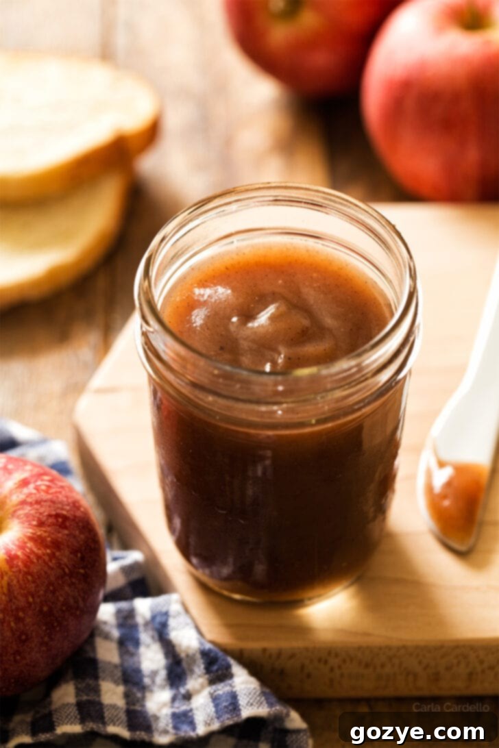 Jar of apple butter on cutting board, ready to be served or stored.