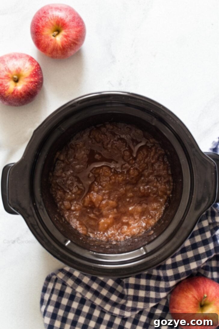 Slow-cooked apples, soft and reduced in volume, in a slow cooker, before blending into apple butter.