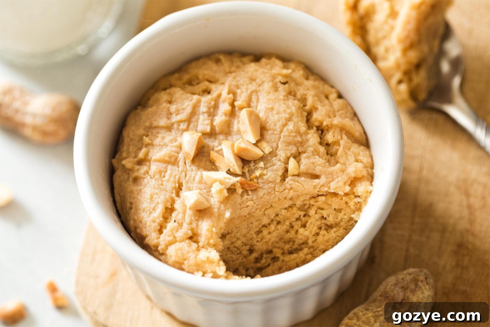 A single-serving microwave peanut butter cookie in a white ramekin with a bite taken out, revealing its soft and tender interior.