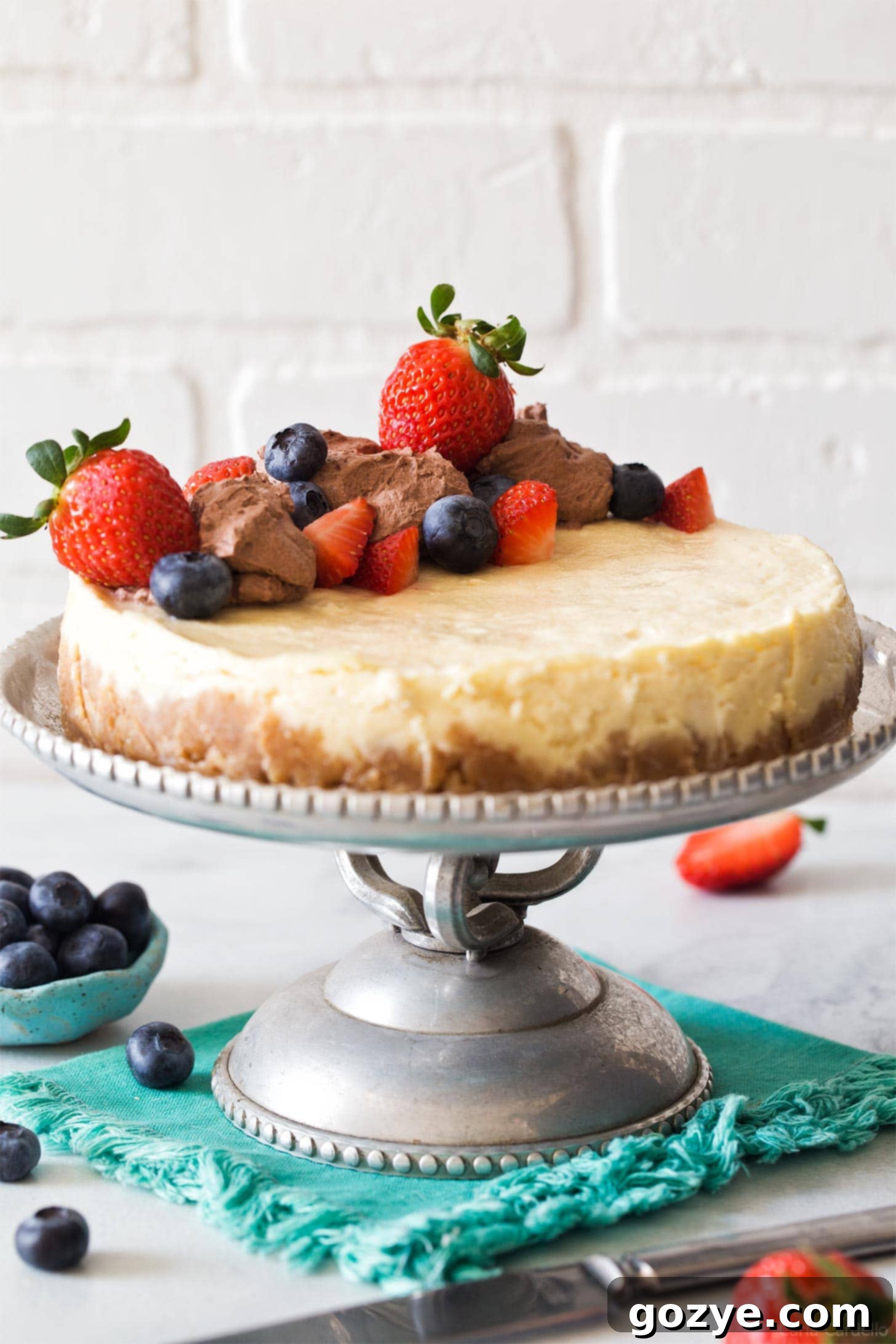 Instant Pot Cheesecake on a silver cake stand, beautifully garnished.
