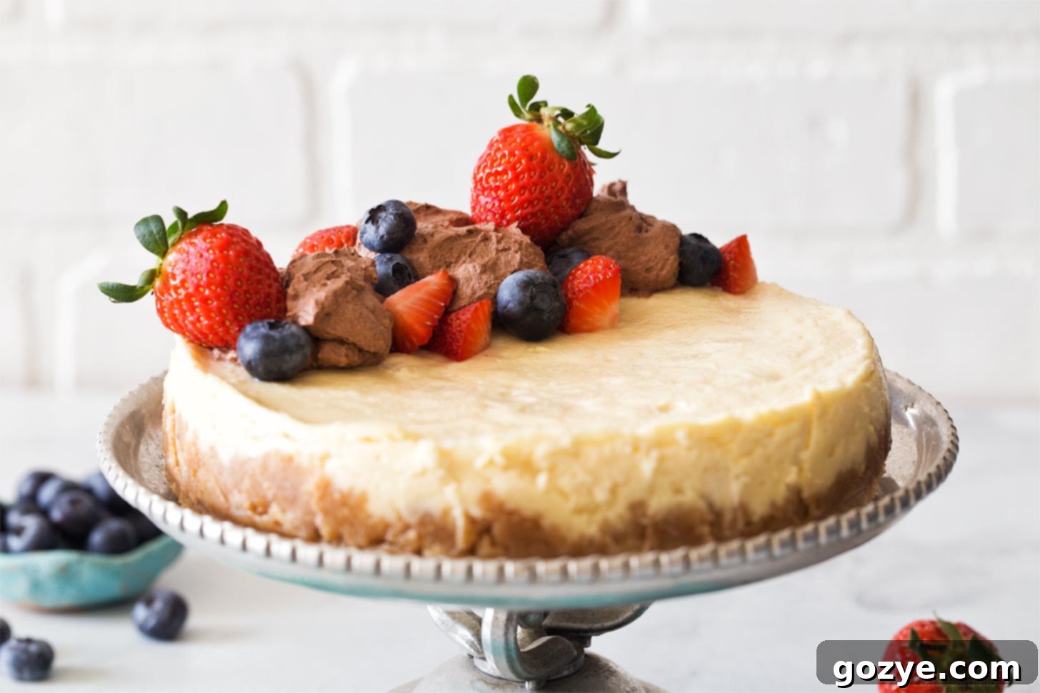 Pressure Cooker Cheesecake presented on a silver cake stand.