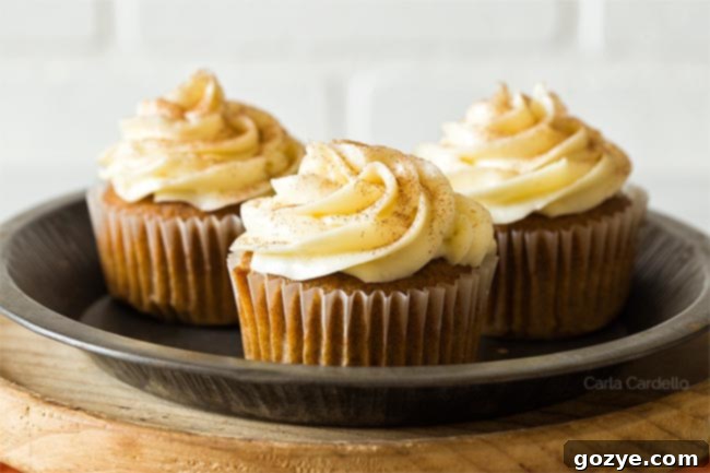 Three pumpkin cupcakes on a plate, showcasing different frosting styles and decorative ideas.