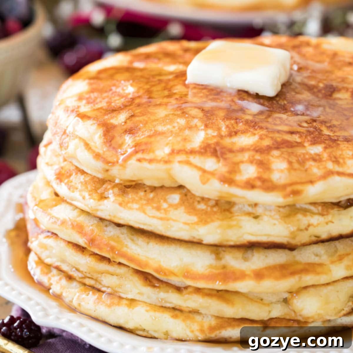 Stack of fluffy buttermilk pancakes with syrup and butter.