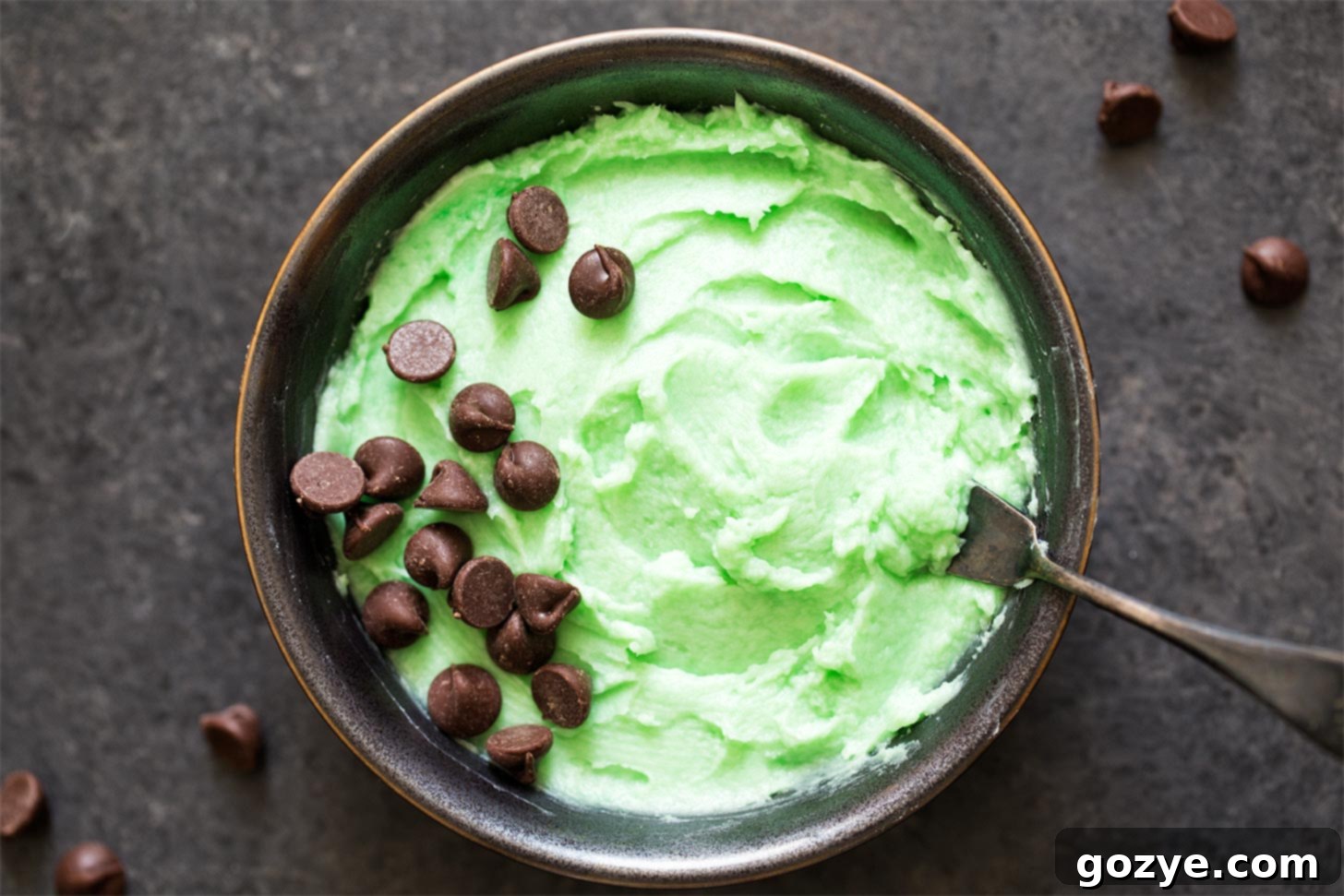 Mint buttercream frosting in a bowl with a knife, showing its readiness.
