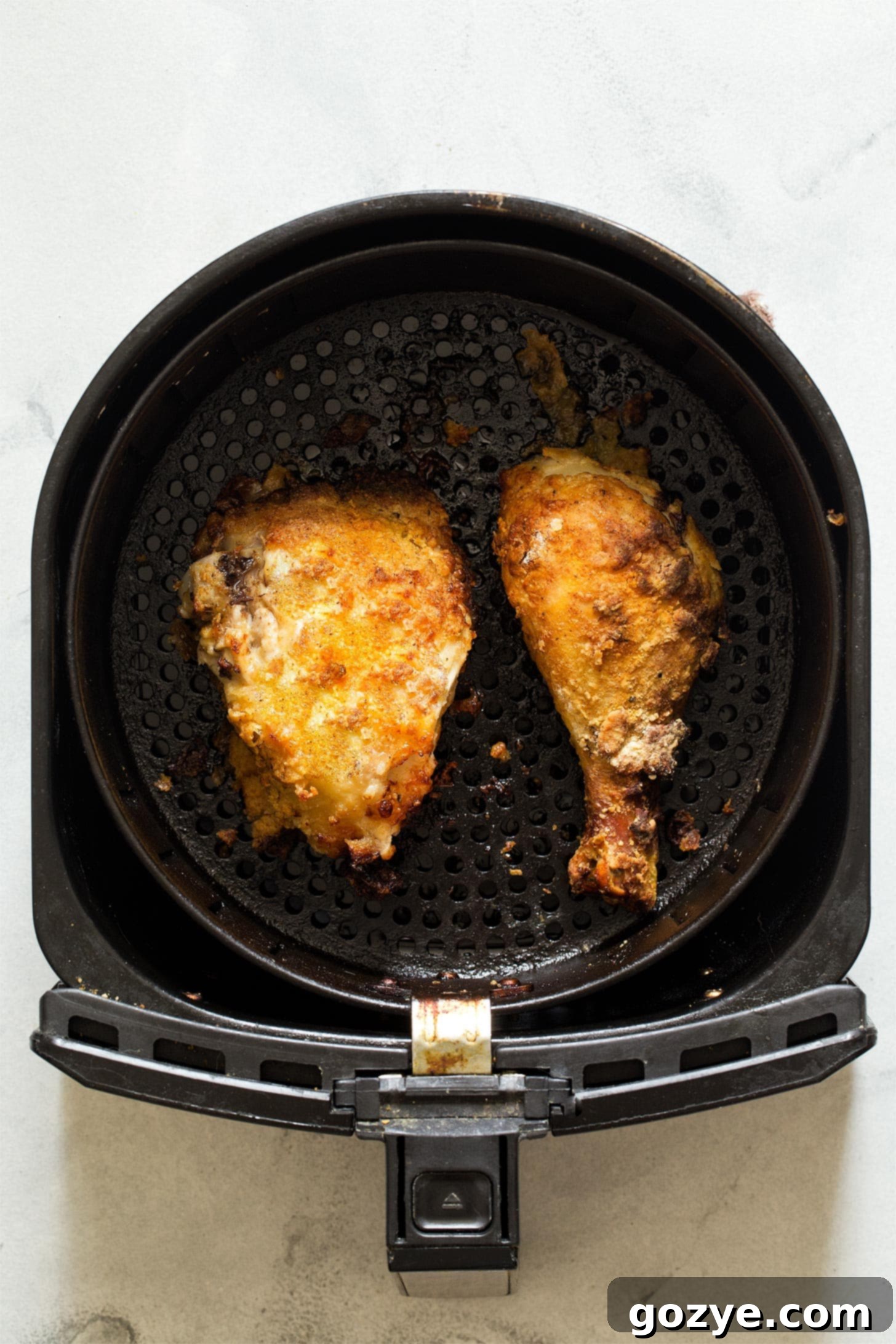 Fried chicken cooking inside an air fryer basket, showing the golden crisping process