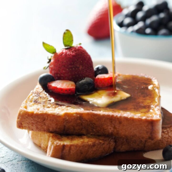 Pouring maple syrup on top of French toast for two with fresh berries