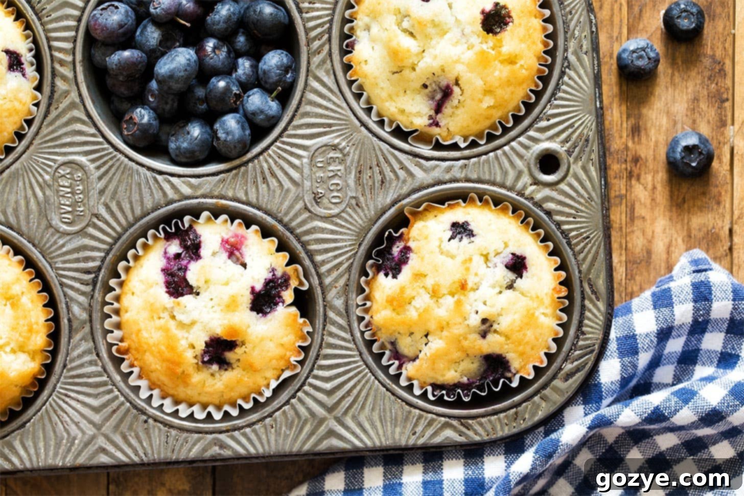 Cozy Small Batch Blueberry Muffins 8 Close up of blueberry muffins in pan with fresh blueberries