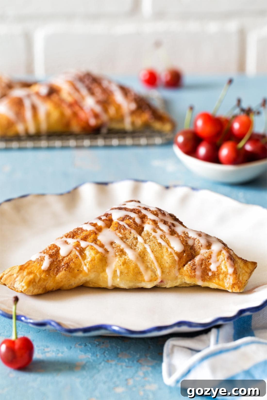 Single Puff Pastry Cherry Turnover with glaze on a white plate, ready to be eaten