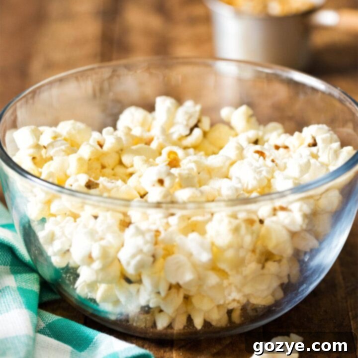 A vibrant photo of a glass bowl filled with fluffy homemade stovetop popcorn, captured from above.