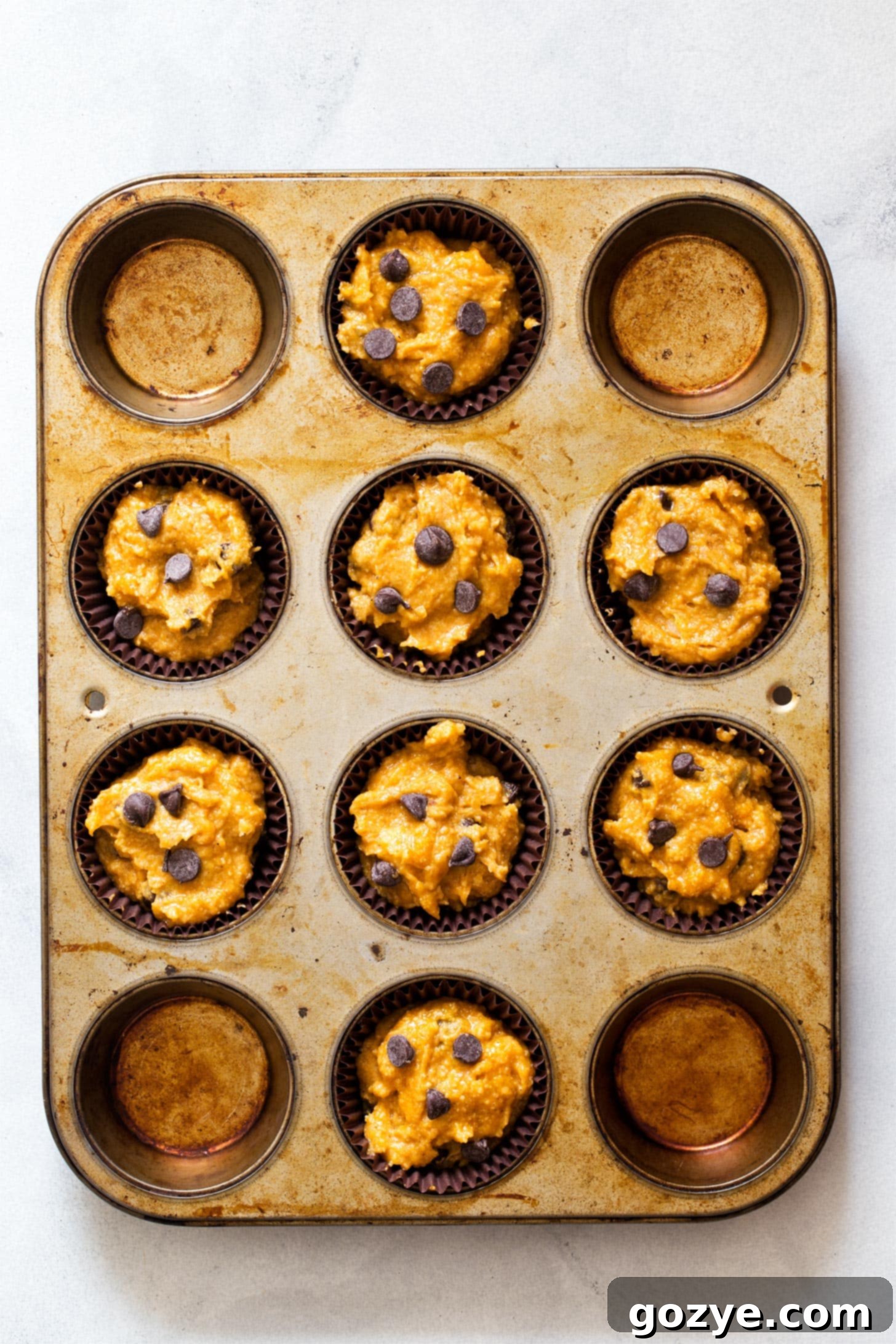Unbaked pumpkin muffin batter in a muffin pan, ready for the oven