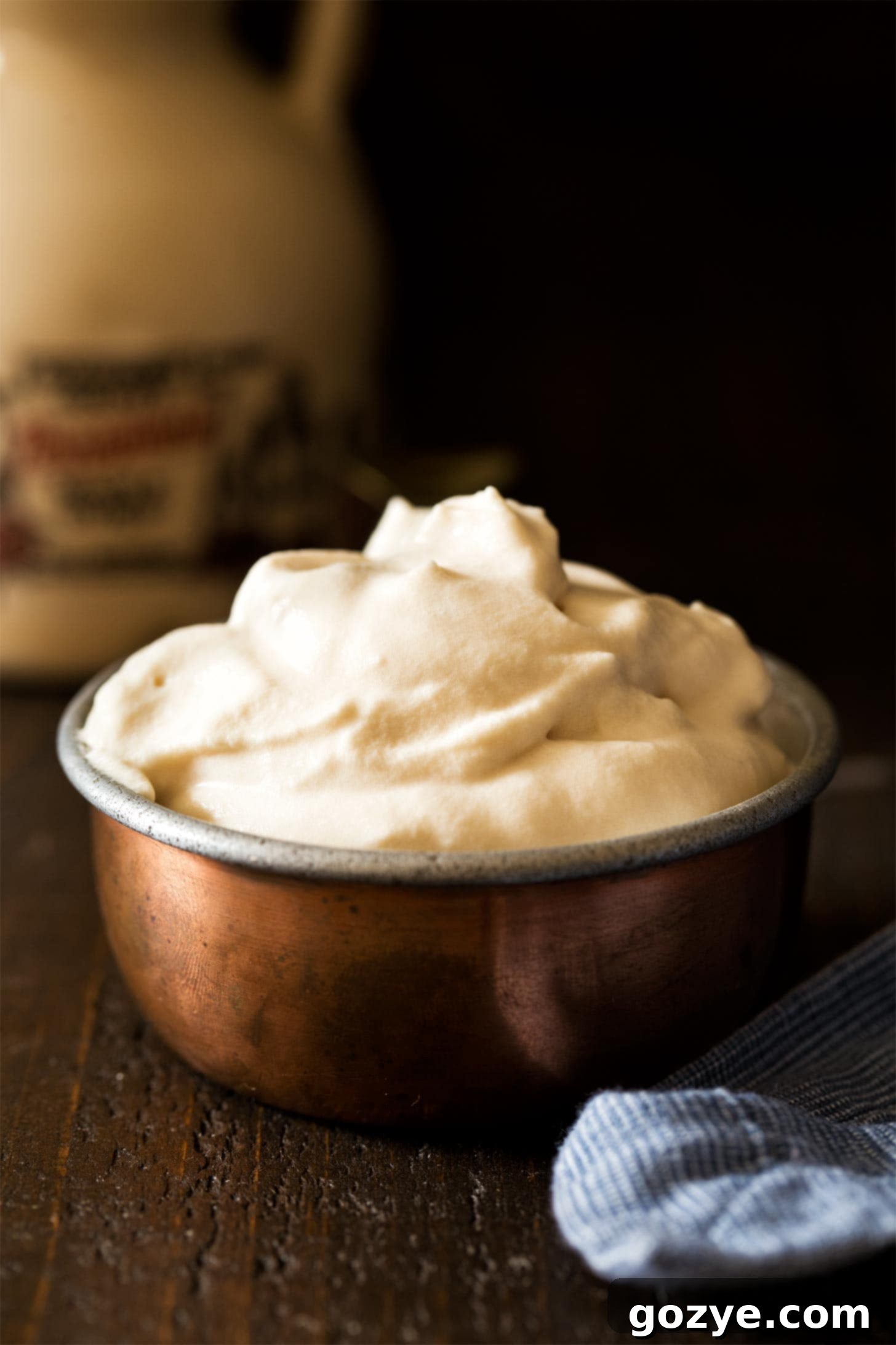 Maple Whipped Cream in a rustic copper cup, showcasing its fluffy texture and golden hue