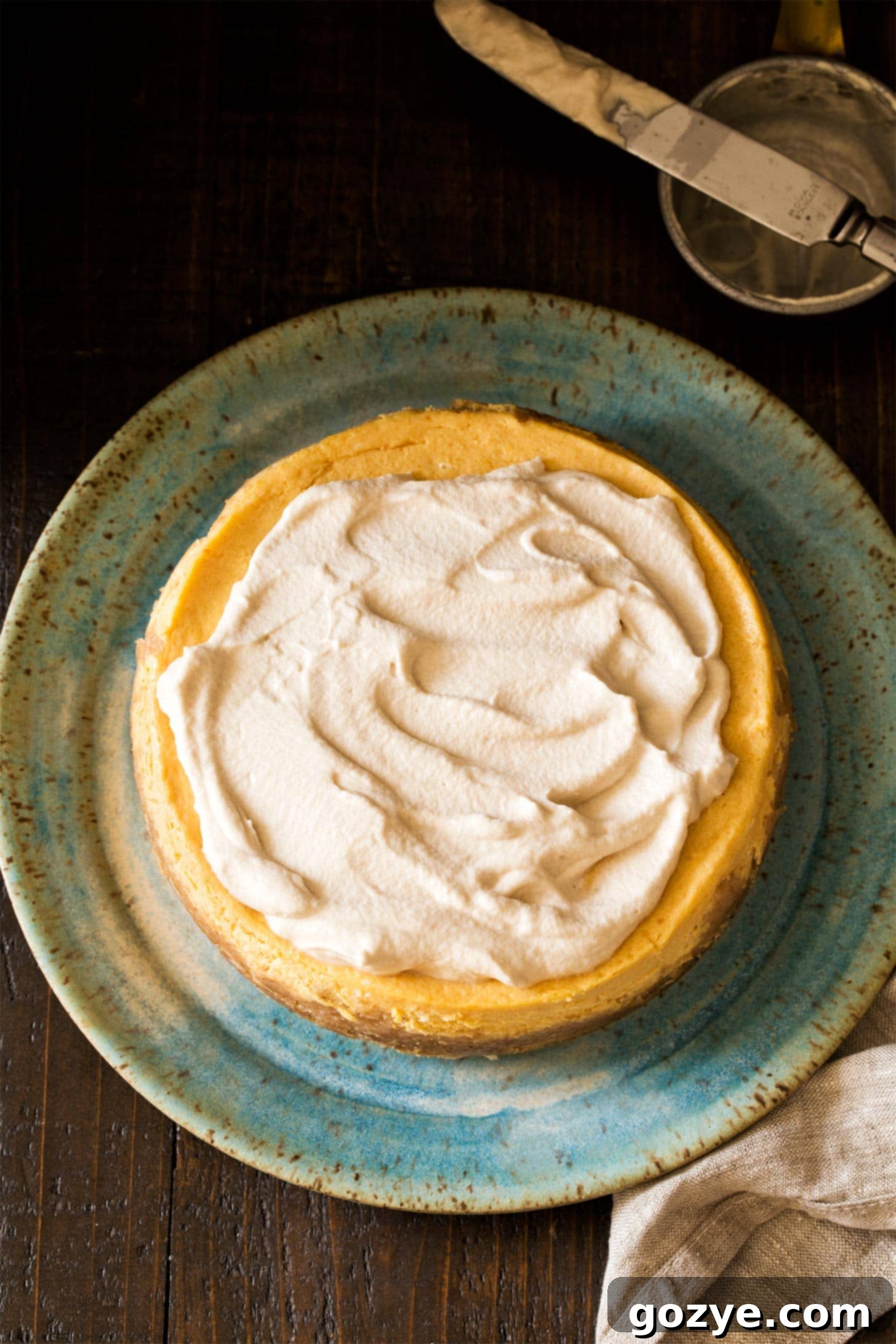 A beautiful slice of pumpkin cheesecake elegantly topped with creamy maple whipped cream, garnished for a perfect autumn dessert
