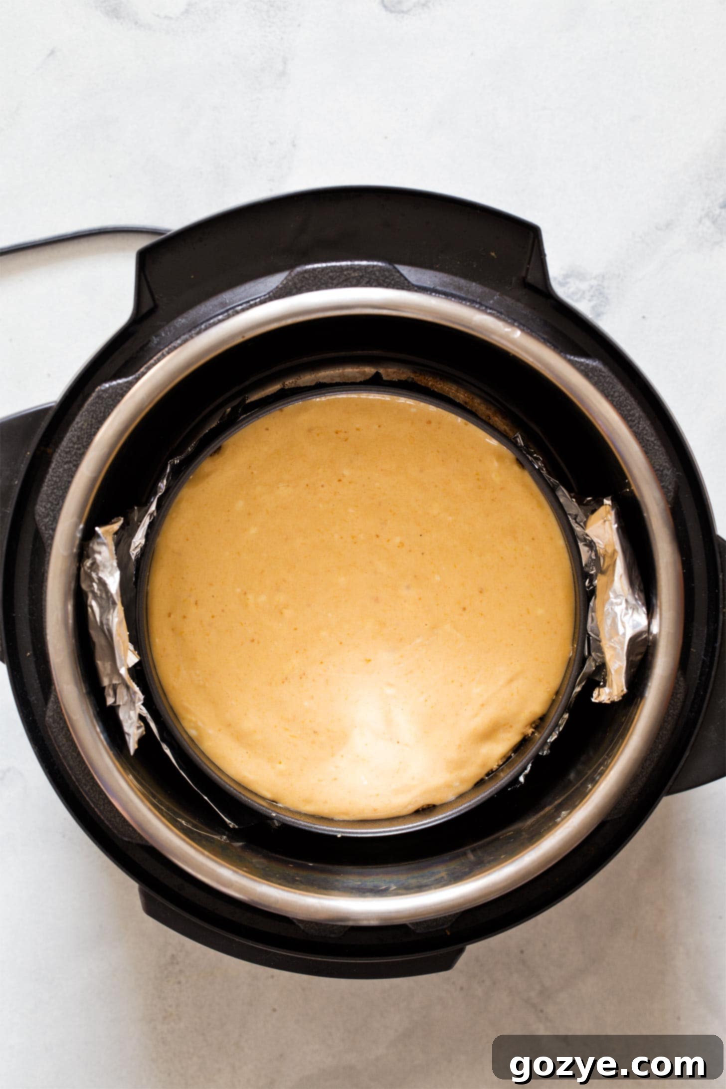Pumpkin cheesecake safely placed inside an Instant Pot with a foil sling, ready for cooking.