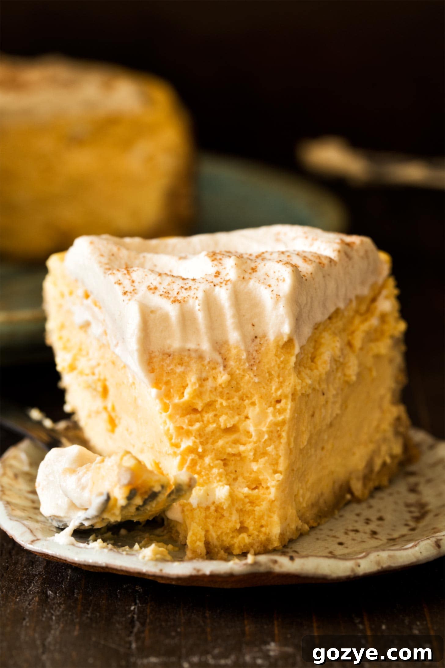 A slice of Instant Pot Pumpkin Cheesecake on a plate, with a small bite taken, highlighting its smooth, creamy texture.