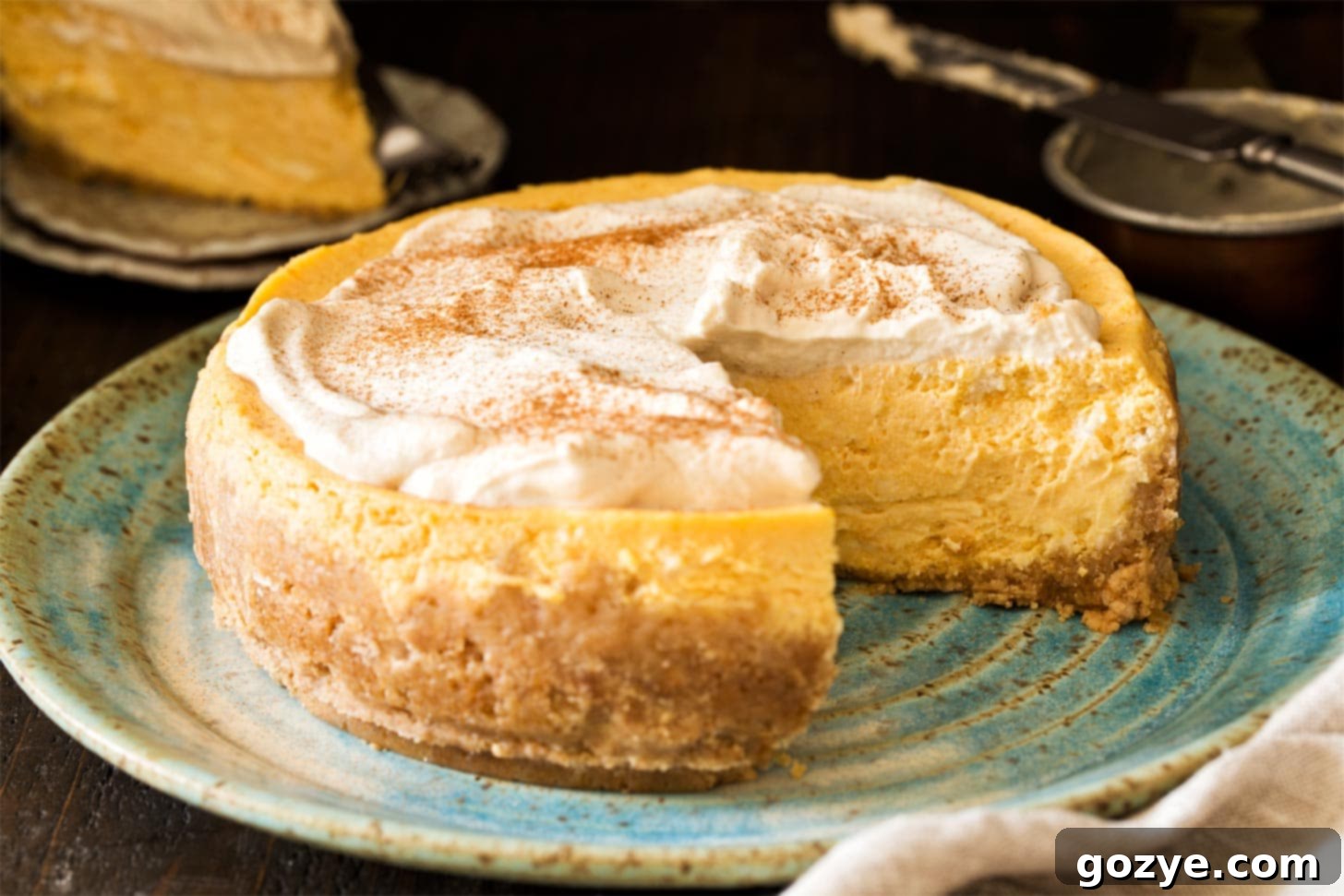 A top-down view of an Instant Pot Pumpkin Cheesecake, with a slice already cut out, revealing the creamy filling and golden crust.