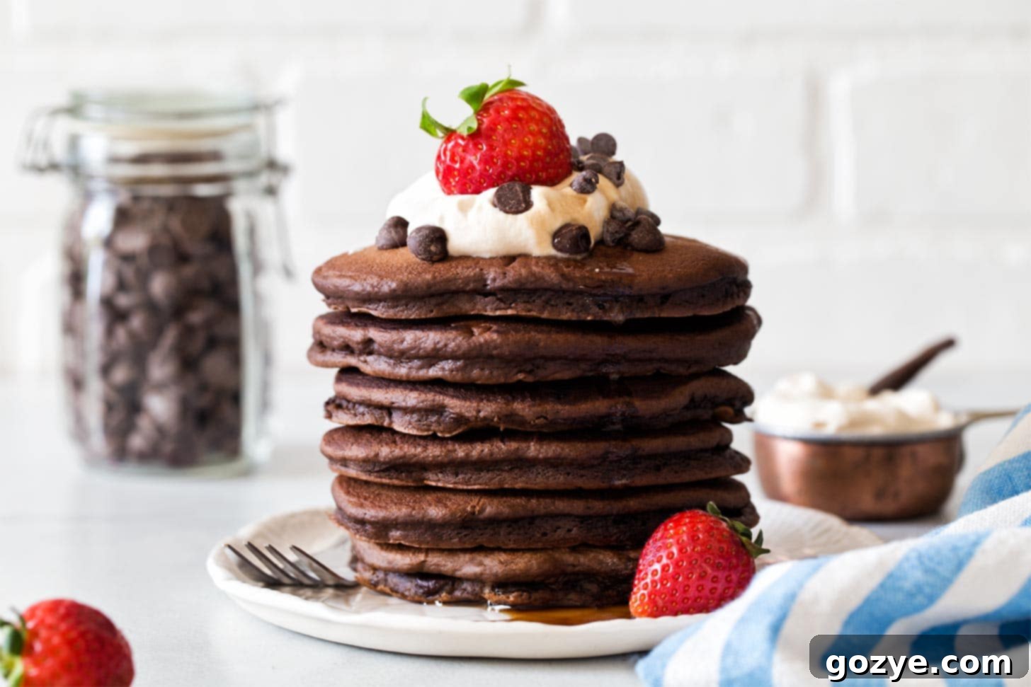 A beautifully presented stack of fluffy chocolate chocolate chip pancakes on a plate, ready to be served
