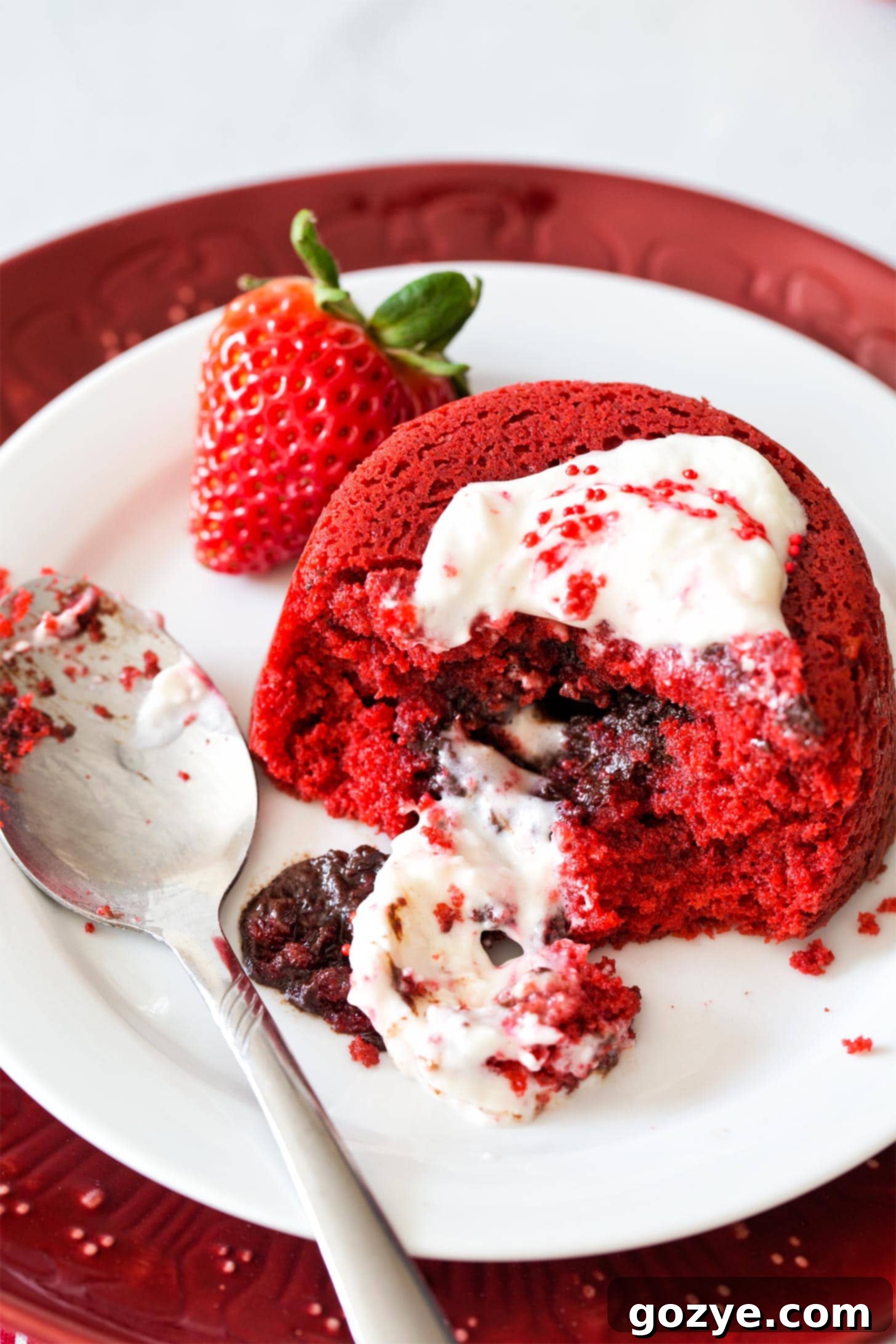 Red Velvet Molten Cakes with cream cheese whipped cream on a plate with spoon