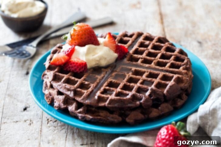 Two perfectly cooked cocoa waffles presented on a vibrant blue plate, ready for various toppings.