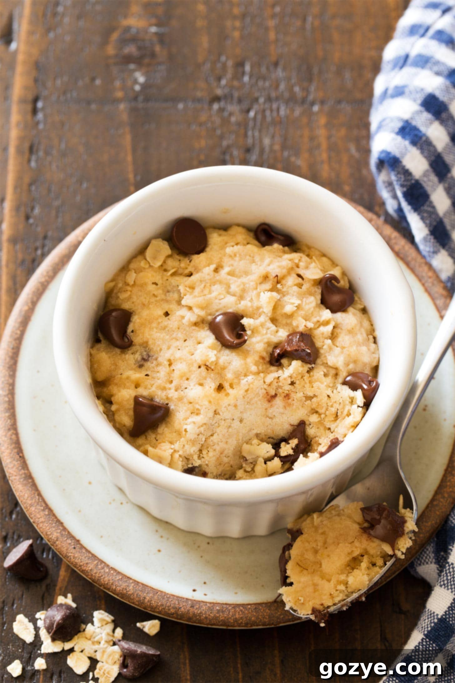 Close-up of a microwave oatmeal cookie in a mug, with a bite taken out, revealing its soft and chewy texture