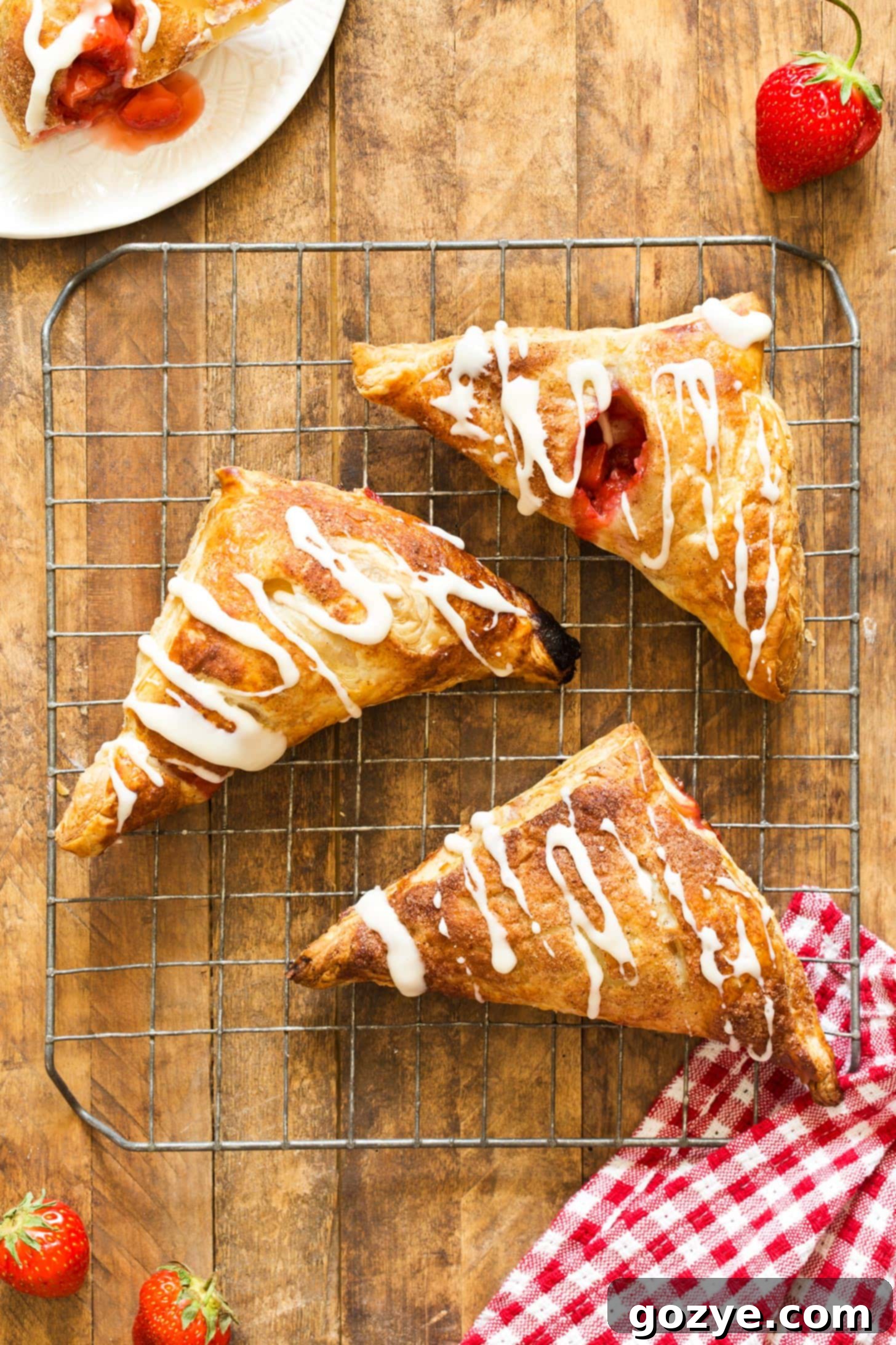 Three strawberry puff pastry turnovers on wire rack
