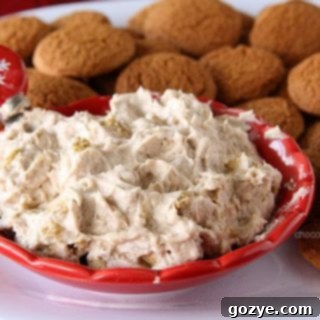 Top-down view of Gingerbread Marshmallow Cheesecake Dip in a white bowl with a spoon.