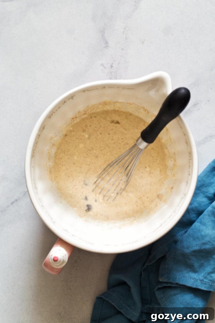 Chocolate chip pancake batter resting in mixing bowl with whisk
