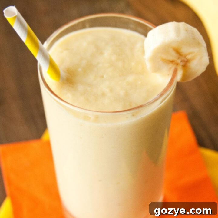 Banana Mango Smoothie in a glass with yellow straw