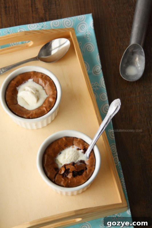 Two perfectly baked deep dish brownies in white ramekins, presented on a rustic wooden tray, ready for a dessert experience.