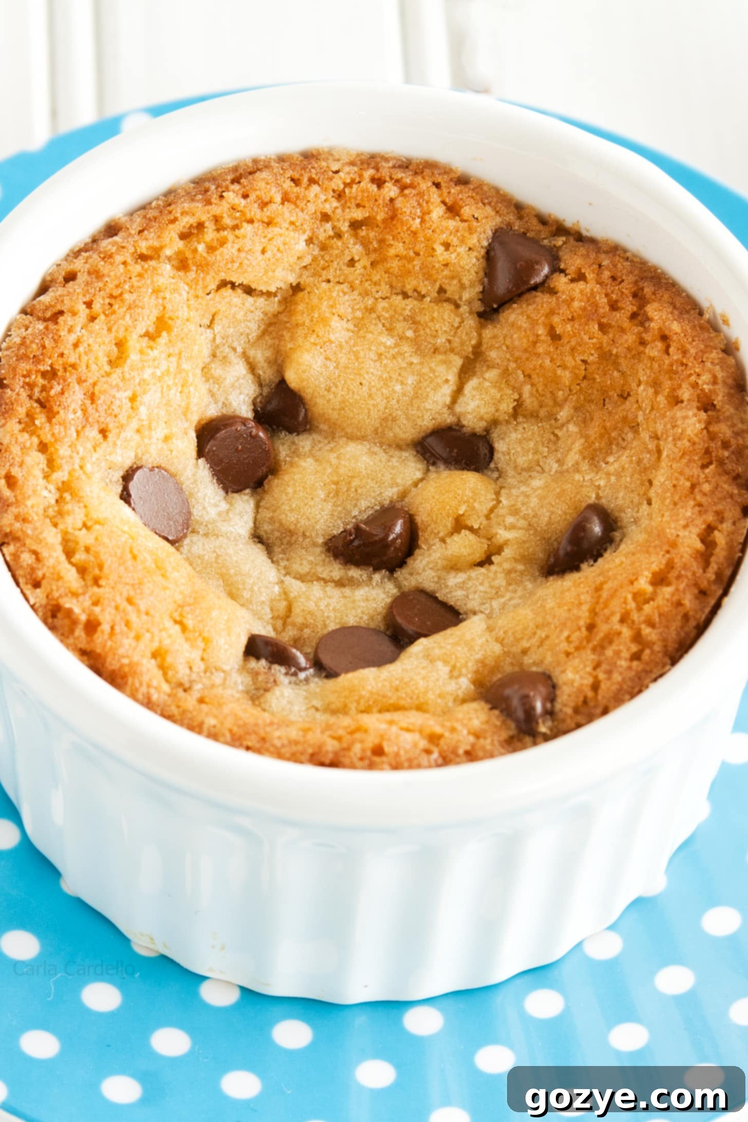 Single Serve Chocolate Chip Cookie in a white ramekin on a blue plate, with a golden-brown top
