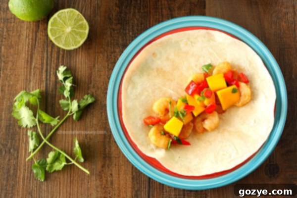 Close-up of Asian Shrimp Tacos filling with marinated shrimp and fresh mango salsa on a tortilla.