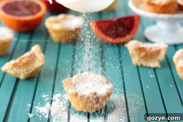 A close-up of a single Blood Orange Pie Bite with a dusting of powdered sugar
