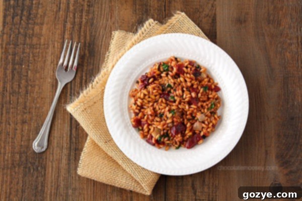 A serving of Beet, Spinach, and Goat Cheese Farro Risotto in a white bowl, garnished with fresh herbs, ready to be enjoyed.