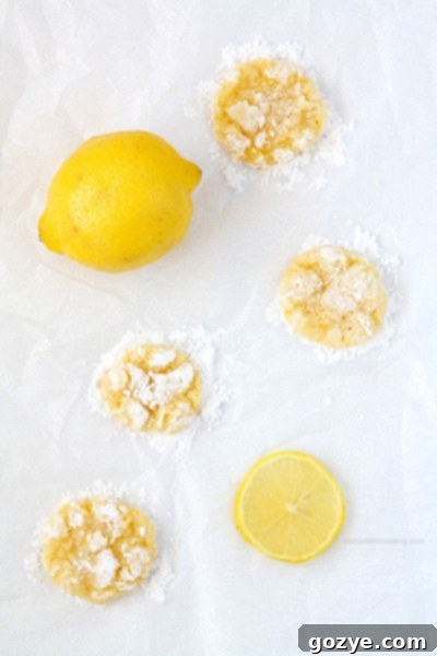 Bright and zesty Lemon Coconut Crinkle Cookies on a cooling rack, glistening with powdered sugar.