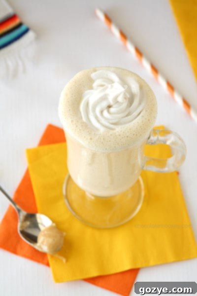 A close-up of a Dulce de Leche Milkshake, with a spoon revealing the thick, creamy texture and a generous swirl of coconut whipped cream on top.
