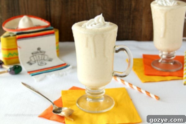 A glass of Dulce de Leche Milkshake showing a slight overflow of whipped cream, a relatable kitchen moment.