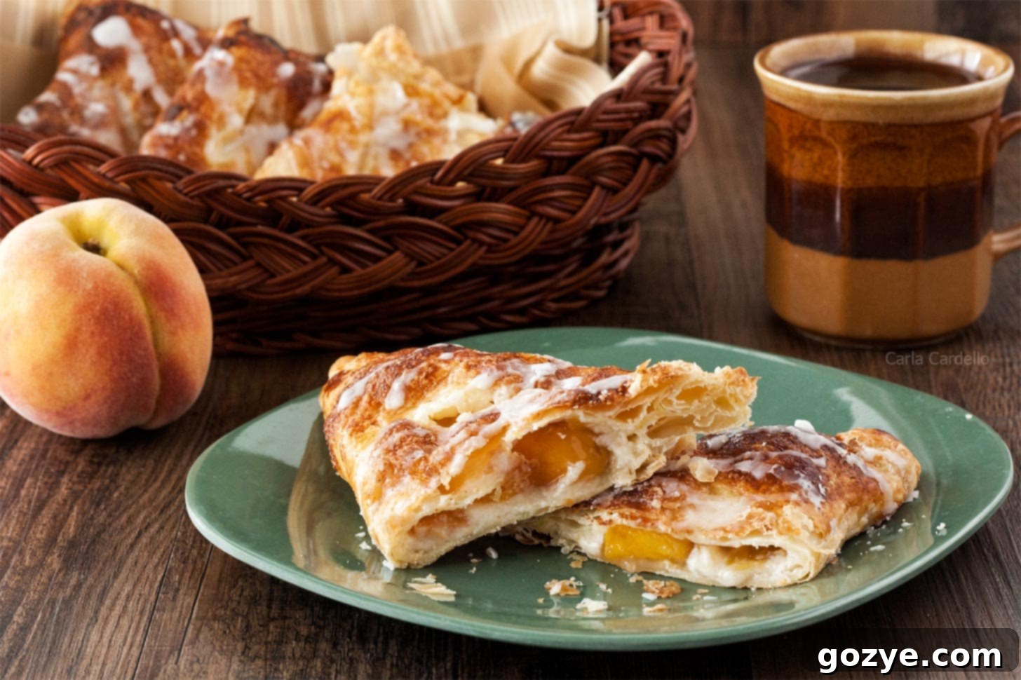 Peach Turnovers cut in half on a plate, showcasing the vibrant filling and flaky layers