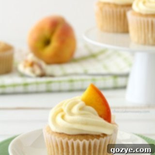 Peaches and Cream Stuffed Cupcakes with frosting and fresh peach slices