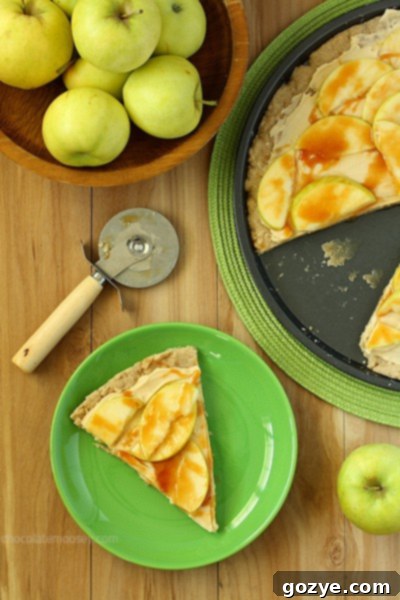 Caramel Apple Sugar Cookie Pizza on a wooden board with a slice removed