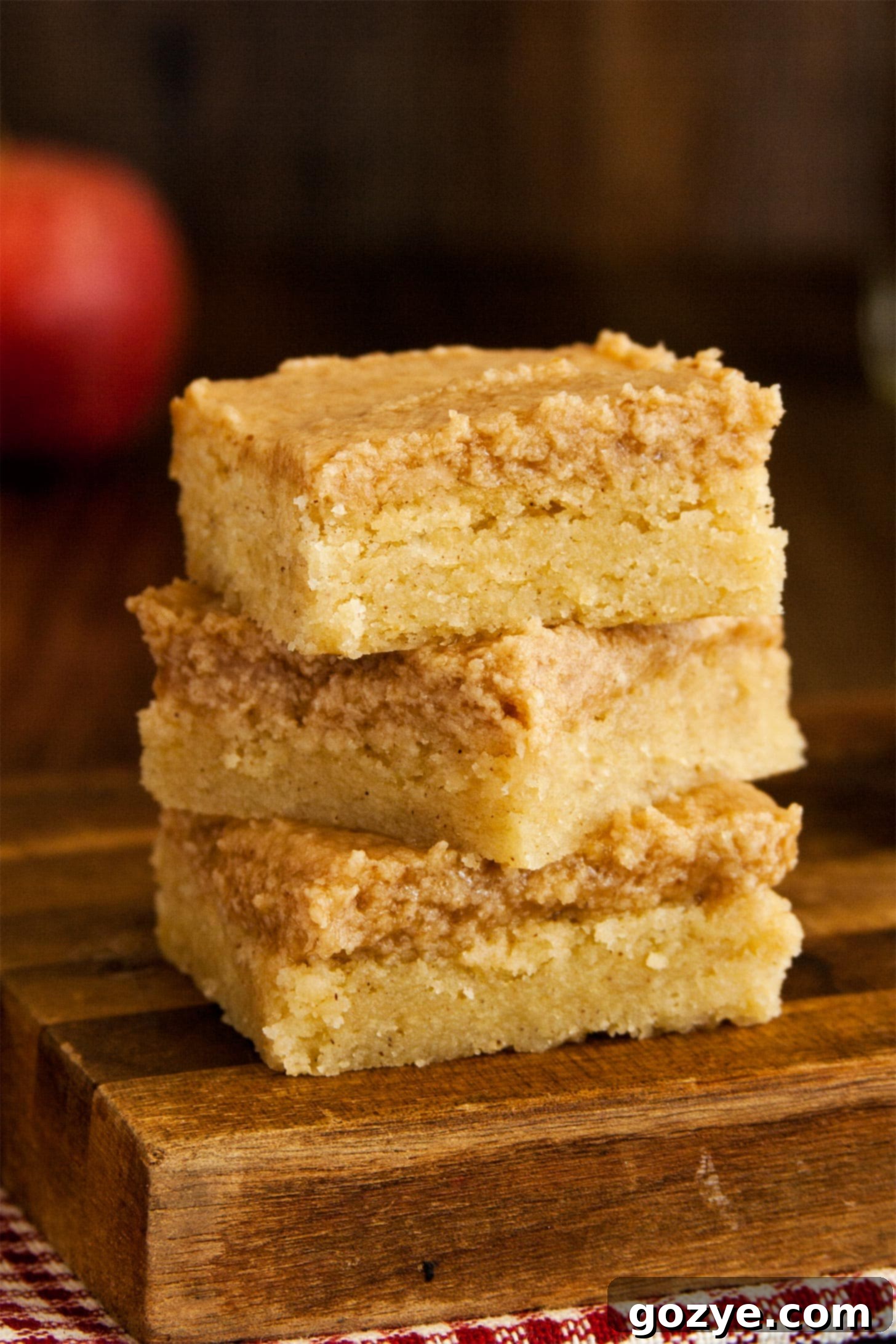 Close up of snickerdoodle cookie bars stacked, showcasing their soft, chewy texture and golden cinnamon-sugar topping