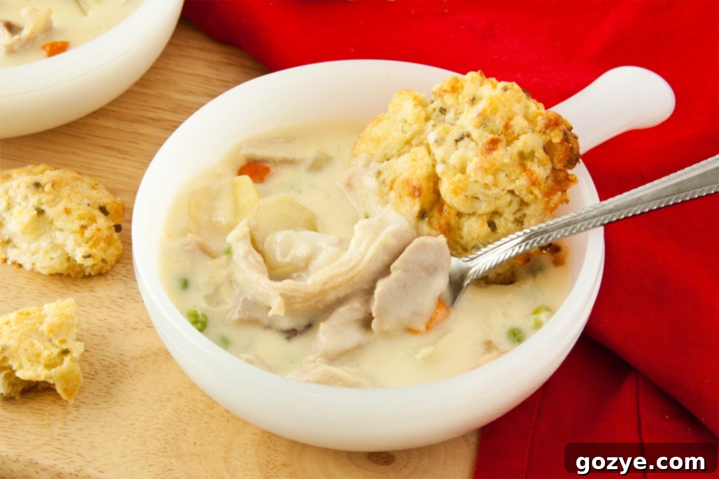 Close up of creamy chicken pot pie soup with a spoon, highlighting the rich broth and ingredients