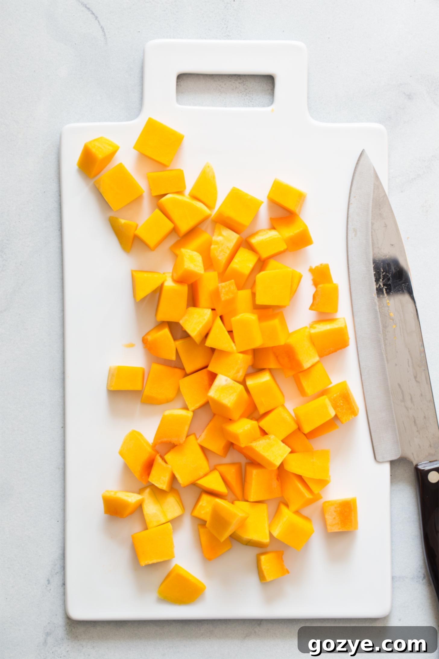 Diced butternut squash cubes, roughly 1-inch in size, spread out on a cutting board, ready for seasoning