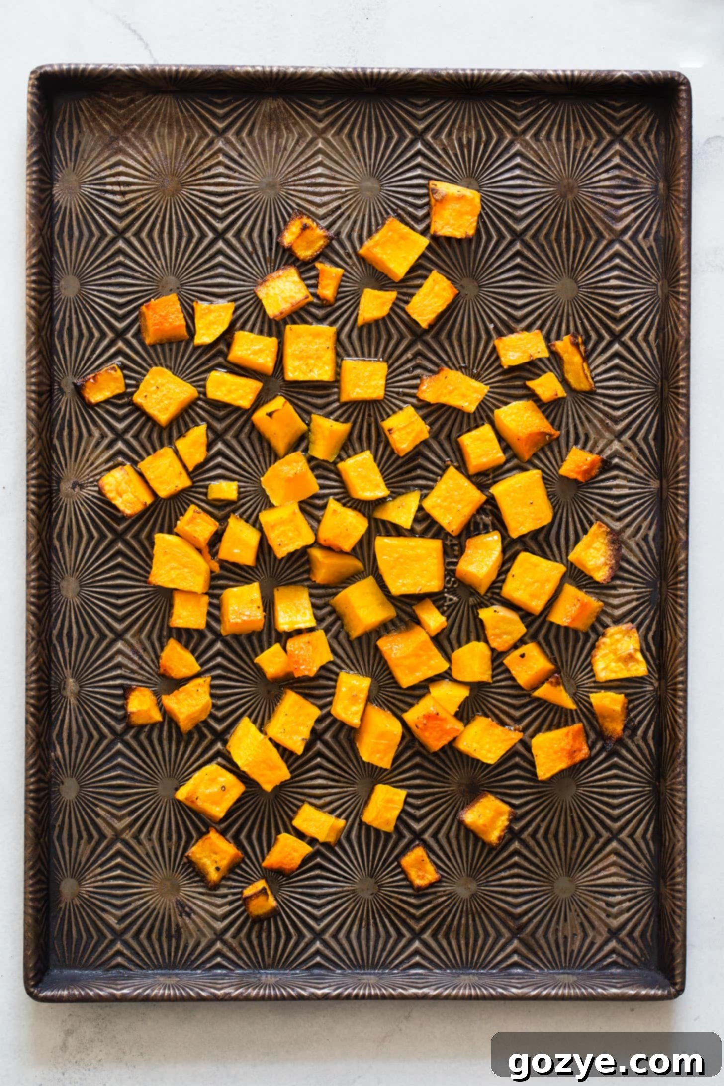 Golden-brown roasted butternut squash cubes spread in a single layer on a baking sheet, fresh from the oven