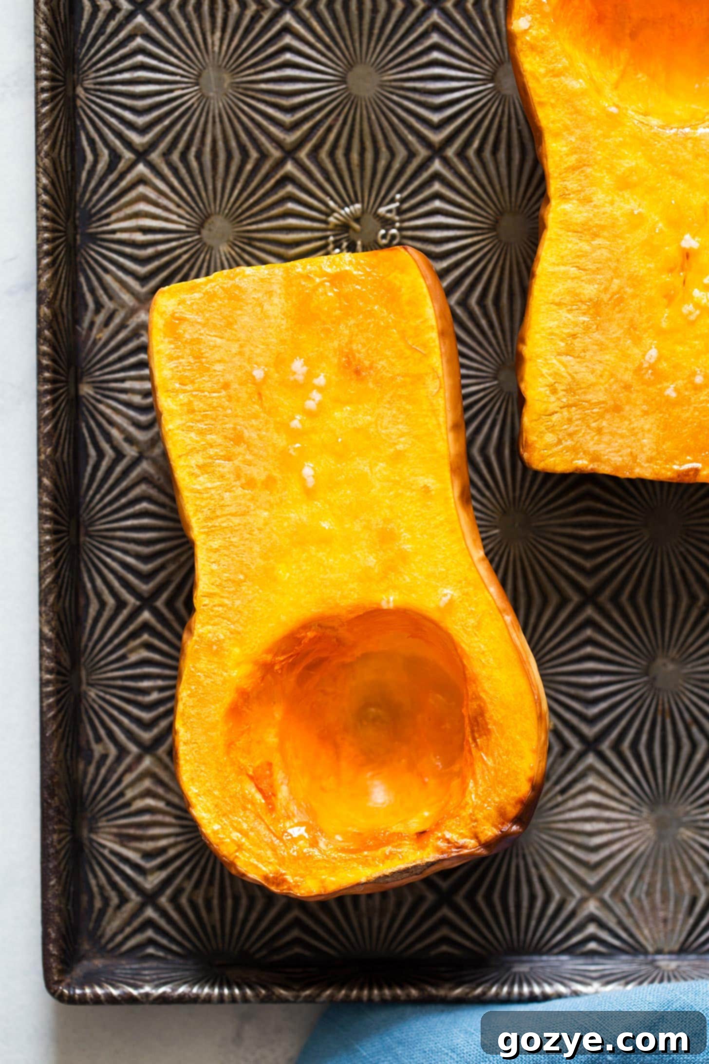 Close-up view of perfectly roasted butternut squash halves, golden-brown and tender on a baking tray