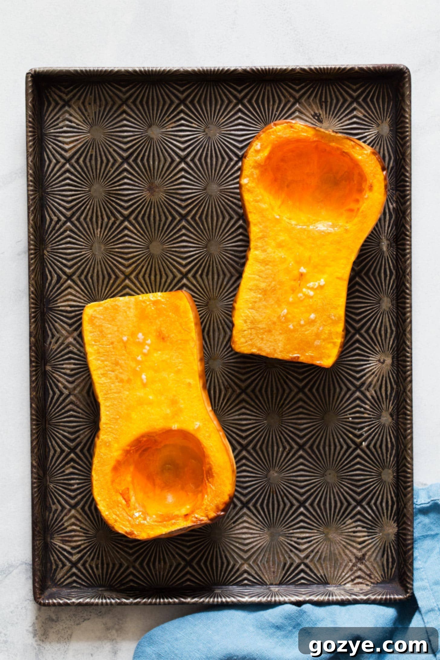 Oven-roasted butternut squash halves, golden-brown and perfectly tender, cooling on a baking tray
